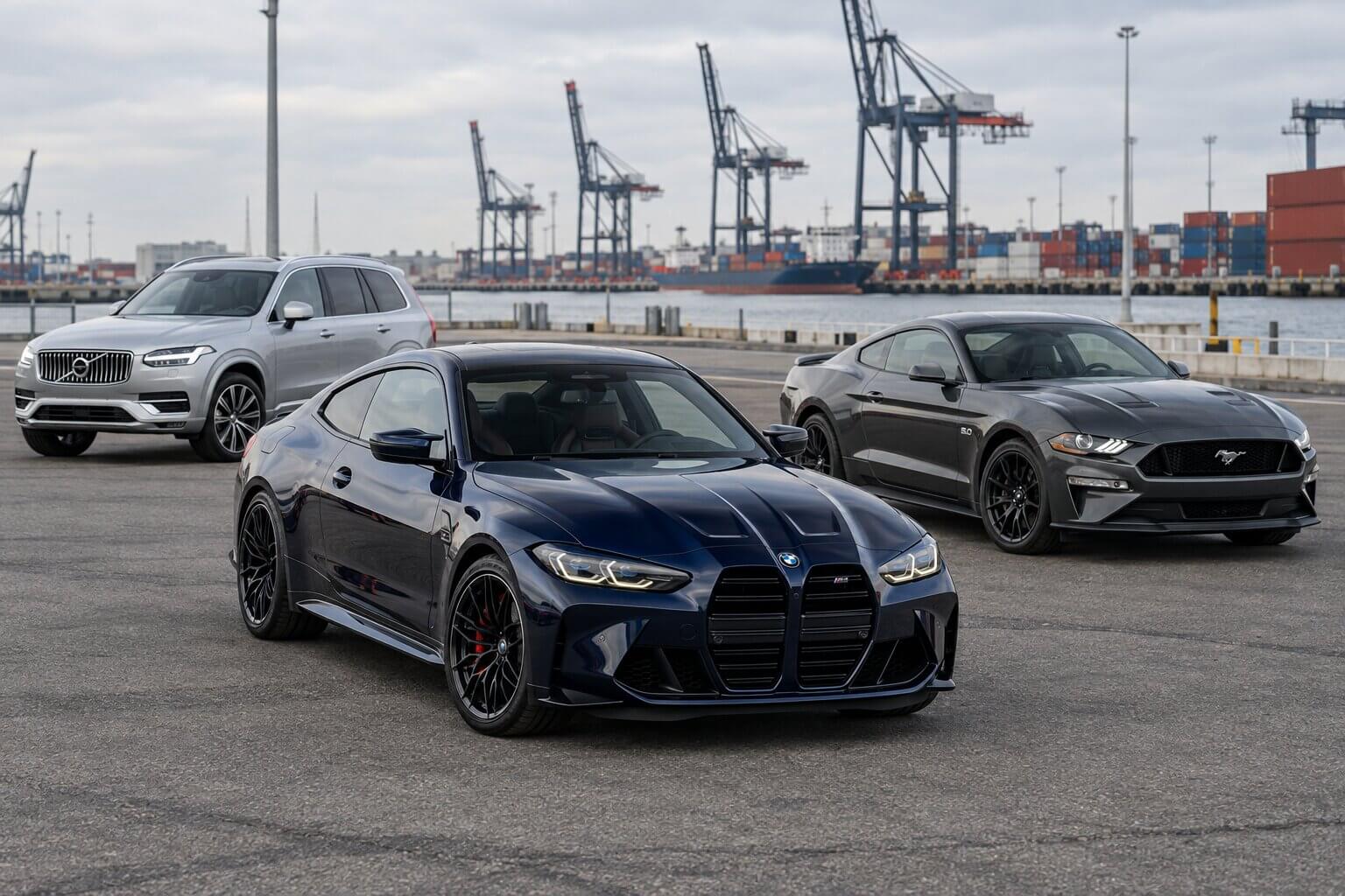 Granatowe BMW, Ford Mustang i SUV przy terminalu portowym